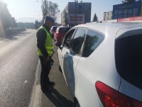 Policjant rozmawia z zatrzymanym do kontroli drogowej kierowcą.