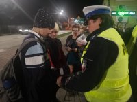 Policjantka zakłada pieszemu opaskę odblaskową.