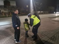 Policjantka zakłada dziecku opaskę odblaskową.