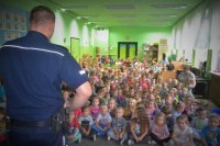 Policjant prowadzi prelekcję z grupą przedszkolaków.