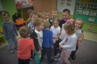 Policjant kuca pomiędzy grupką dzieci.