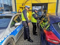 Policjanci z drogówki rozmawiają ze sprawcą wykroczenia drogowego.