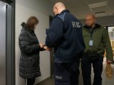 Policjanci zakładają podejrzanej kajdanki.