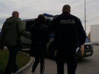 Policjanci prowadzą podejrzaną do radiowozu.