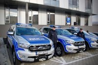 Policjanci stoją przy nowych radiowozach.