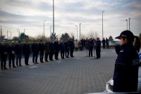 Policjantka stoi przy radiowozie, na drugim planie kadra bielskiej policji.
