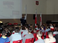 Policjant prowadzi prelekcję dla młodzieży w szkole.