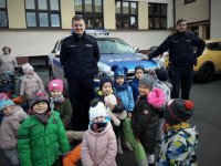 Policjanci razem z dziećmi stoją przy terenowym radiowozie.