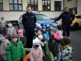 Policjanci razem z dziećmi stoją przy terenowym radiowozie.
