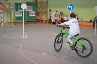 Dziecko - uczestnik turniej wiedzy o ruchu drogowym pokonuje tor przeszkód na rowerze.