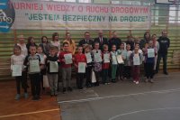 Uczestnicy i organizatorzy turnieju wiedzy o ruchu drogowym na wspólnym zdjęciu na sali gimnastycznej.