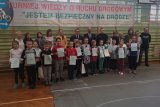 Uczestnicy i organizatorzy turnieju wiedzy o ruchu drogowym na wspólnym zdjęciu na sali gimnastycznej.