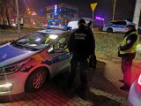 Policjant i funkcjonariusz Służby Celnej stoją przy policyjnym radiowozie.
