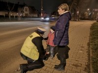 Policjantka zakłada dziecku opaskę odblaskową.