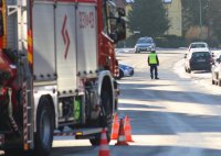 Wóz strażacki, w tle policjant na drodze.