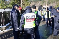 Policjanci dowodzący akcją rozmawiają ze strażakiem.