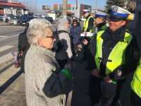 Policjanci rozmawiają z kobietą przy przejściu dla pieszych.