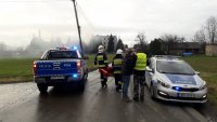 Policyjne radiowozy stoją w rejonie pożaru. Na drugim planie budynek, z którego wydobywa się dym.