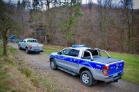 Wóz Straży Leśnej i Policji stoją przed wjazdem do lasu.