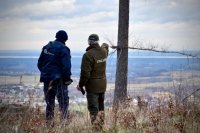 Strażnik Leśny pokazuje Policjantowi ręką miejsce na panoramie Jaworza.