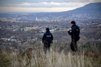 Policjanci schodzą w dół pagórka. W tle panorama Jaworza i Bielska-Białej.
