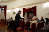 Policjant rozdaje seniorom ulotki informacyjne.