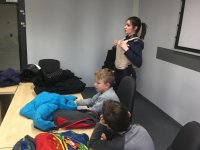 Policjanci i dzieci ze szkoły podstawowej podczas zajęć zorganizowanych na komendzie.