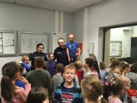 Policjanci i dzieci ze szkoły podstawowej podczas zajęć zorganizowanych na komendzie.