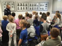 Policjanci i dzieci ze szkoły podstawowej podczas zajęć zorganizowanych na komendzie.