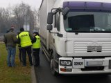 Policjanci i inspektor WIOŚ kontrolują ciężarówkę, razem z kierowcą stoją obok pojazdu.
