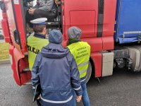 Policjanci i inspektor WIOŚ kontrolują ciężarówkę.