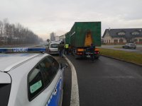 Policyjny radiowóz stoi obok ciężarówki. Przy niej stoją policjanci z inspektorem WIOŚ i kierowcą.