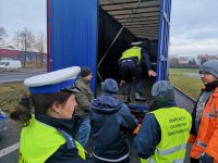 Policjanci i inspektor WIOŚ kontrolują ciężarówkę. Jeden z policjantów wchodzi do naczepy pojazdu.