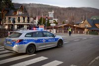 Policyjny radiowóz dojeżdża do skrzyżowania.