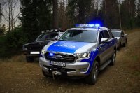 Policyjny radiowóz stoi przy kontrolowanym samochodzie terenowym.
