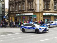 Dwa policyjne radiowozy stoją w rejonie skrzyżowania, przez które prowadzi trasa świątecznego korowodu.