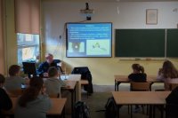 Policjantka prowadzi prelekcję w szkolnej klasie.