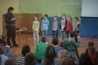 Policjantka z ruchu drogowego prowadzi konkurs z dziećmi na sali gimnastycznej.