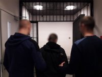 Policjanci wprowadzają podejrzanego o kradzież do celi.