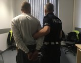 Policjant ruchu drogowego trzyma zatrzymanego nietrzeźwego kierującego.