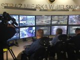 Strażnicy miejscy i policjant obserwują na monitoringu miejskim zachowanie kierowców i pieszych.