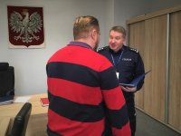 Komendant policji składa podziękowanie kierowcy, który pomógł zatrzymać nietrzeźwego kierującego. Kierowca stoi obrócony plecami do kamery, na drugim planie policjant, rozmawiają.