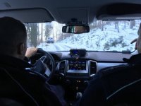Policjanci jadą leśną drogą za terenówką. Widok z kabiny kierowcy.