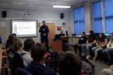 Policjant prowadzi prelekcję w klasie szkoły podstawowej.