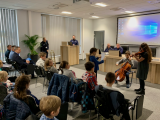 Dzieci grają na instrumentach na sali odpraw, W tle muzyki słuchają policjanci.