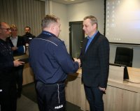 Komendant miejski składa gratulację policjantowi w ubiorze cywilnym.