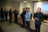 Policjanci odchodzący na emeryturę stoją na sali odpraw podczas uroczystej zbiórki.