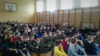 Młodzież zgromadzona na sali gimnastycznej podczas prelekcji policjanta.