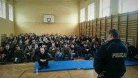 Młodzież zgromadzona na sali gimnastycznej podczas prelekcji policjanta.