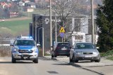 Policyjny radiowóz jedzie ulicą, w tle budynek komendy miejskiej.